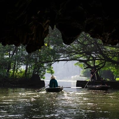 Chiếc thuyền chở khách đi vào hang sông dưới vách đá nhô ra.